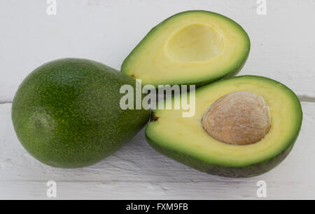 Photo of whole and cut avocados on rustic white wood table Stock Photo