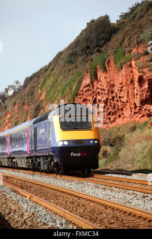 A diesel locomotive on the South Devon railway near Dawlish with red cliffs behind Stock Photo