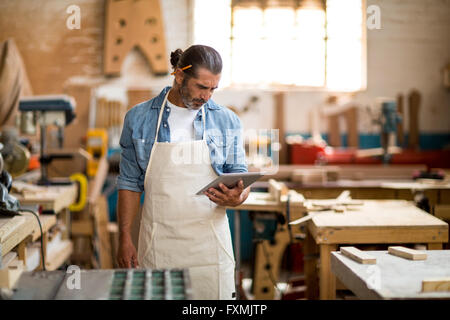 Carpenter using digital tablet in workshop Stock Photo