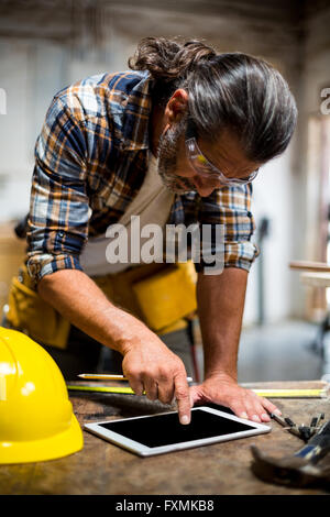 Carpenter using digital tablet in workshop Stock Photo