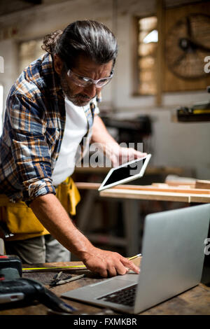 Carpenter using digital tablet and mobile phone Stock Photo
