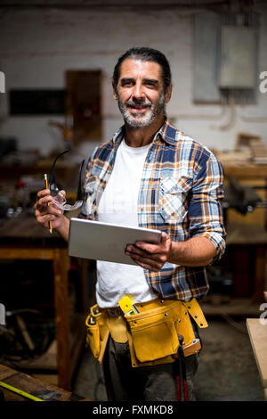 Carpenter using digital tablet in workshop Stock Photo