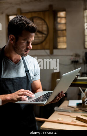 Carpenter using laptop in workshop Stock Photo