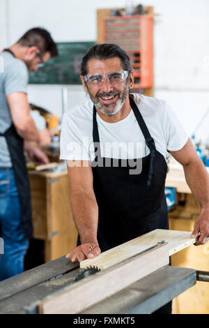 Carpenter using table saw for cutting wood at workbench Stock Photo