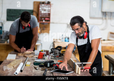 Carpenter using digital tablet in workshop Stock Photo