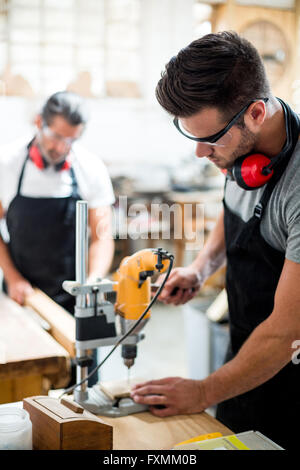 Carpenter drilling a hole in a wooden plank Stock Photo