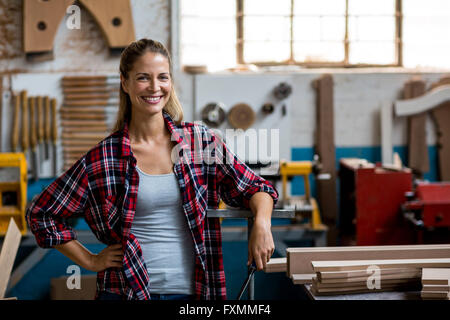 Happy female carpenter standing in workshop Stock Photo