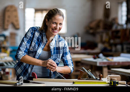 Female carpenter using chisel on wooden plank Stock Photo