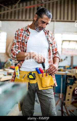 Carpenter removing chisel from tool belt Stock Photo