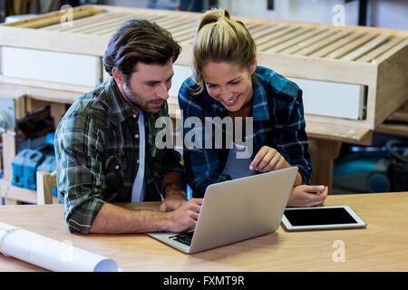 Male and female carpenters using laptop in workshop Stock Photo