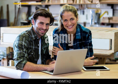 Male and female carpenters using laptop in workshop Stock Photo