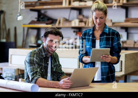 Male and female carpenters using digital tablet and laptop Stock Photo