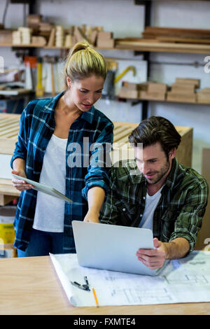 Male and female carpenters using digital tablet and laptop Stock Photo