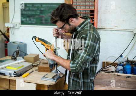 Carpenter drilling a hole in a wooden plank Stock Photo