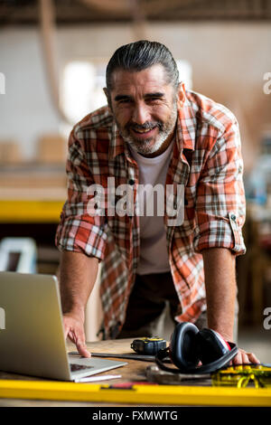 Happy carpenter using laptop Stock Photo