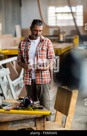 Carpenter using digital tablet in workshop Stock Photo