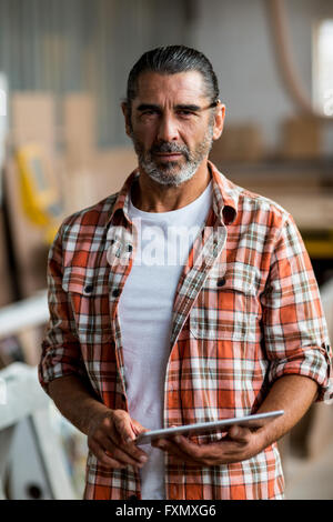 Confident carpenter using digital tablet in workshop Stock Photo
