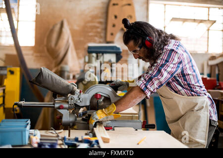 Carpenter cutting wooden plank with circular saw Stock Photo