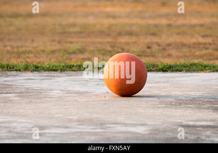 The old basketball ball on the floor in the evening. (outdoor) in Thailnd Stock Photo