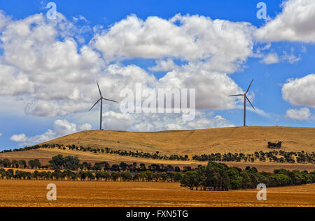 2 tall wind turbines generating electricity in rural South Australia on a hill top above cultivated harvested farm fields. Stock Photo