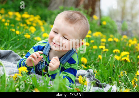 Happy little boy lying on meadow in spring Stock Photo