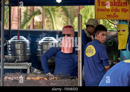 Face mask. Chef cooking at an outdoor market BBQ stall and wearing full face mask to protect against the heat. Thailand S. E. Asia Stock Photo