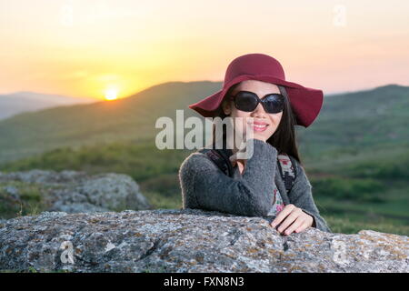 Female hiker enjoying sunset while sitting on a rock Stock Photo