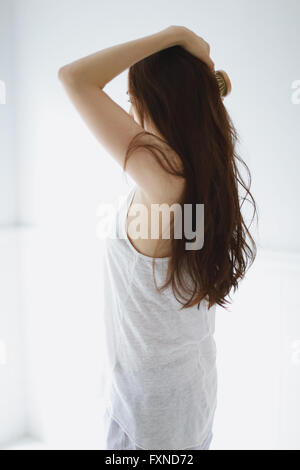 Young attractive Japanese woman doing her hair in the bathroom Stock Photo