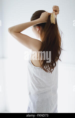 Young attractive Japanese woman doing her hair in the bathroom Stock Photo