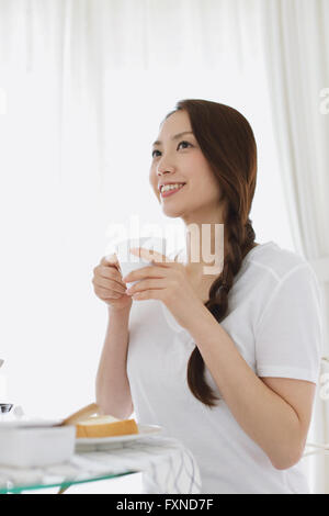 Young attractive Japanese woman having breakfast at home Stock Photo