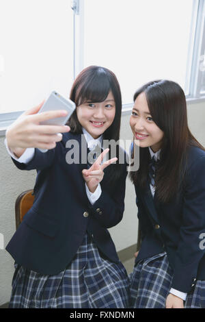 Japanese high-school students taking selfie in classroom Stock Photo