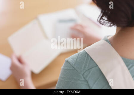 Senior Japanese woman doing accounting in the living room Stock Photo