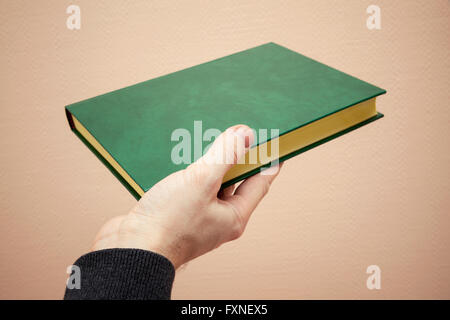 Book with empty dark green leather cover in male hand, old style warm tonal correction photo filter effect Stock Photo