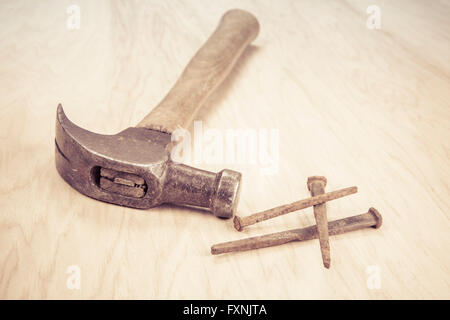 Old wooden hammer and square nails on a wood background. Stock Photo