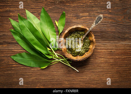 Wild garlic leafs and pesto on wooden background overhead shoot Stock Photo