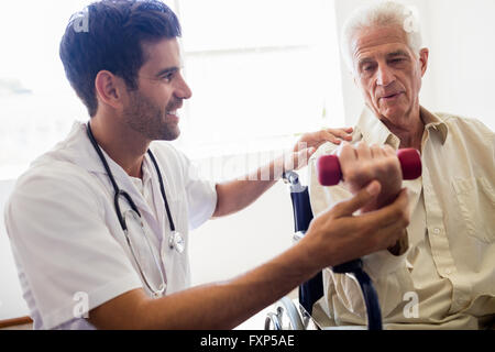 Nurse helping senior man with doing exercises Stock Photo