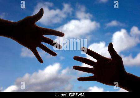 Silhouette of two hands reaching towards each other. Stock Photo