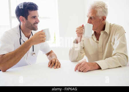 Nurse and senior man drinking coffee Stock Photo