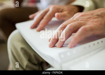 Blind senior man using braille to read Stock Photo