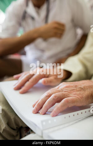 Blind senior man using braille to read Stock Photo