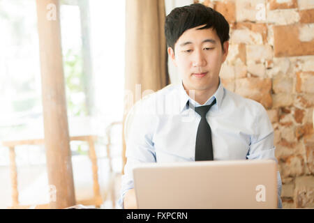 Young Asian businessman working with his laptop in outdoor scene Stock Photo