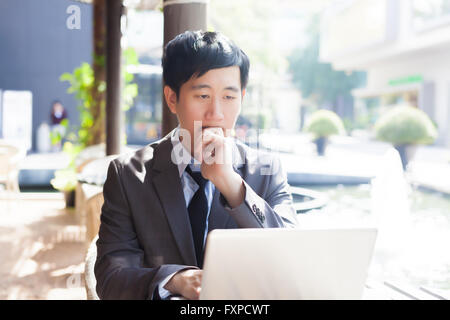 Young Asian casual businessman thinking while working in outdoor scene Stock Photo