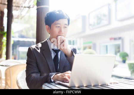 Young Asian casual businessman thinking while working in outdoor scene Stock Photo