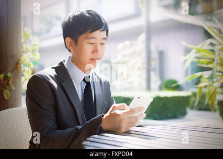Young Asian businessman using phone in the outdoor scene Stock Photo