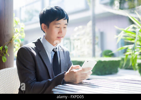 Young Asian businessman using phone in the outdoor scene Stock Photo