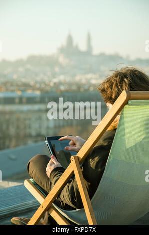 Man using digital tablet on rooftop terrace Stock Photo
