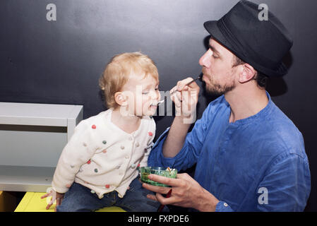 Father spoon feeding toddler Stock Photo