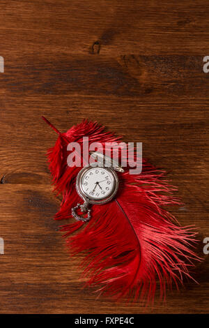 Vintage pocket watch over a red feather Stock Photo
