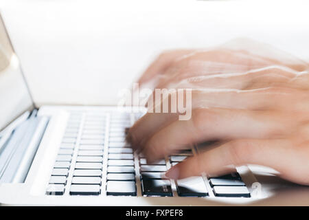 Human Hands typing on laptop in blurred motion with copy space above (selective focus) Stock Photo