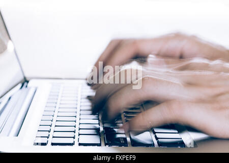 Human Hands typing on laptop in blurred motion with copy space above (selective focus) Stock Photo